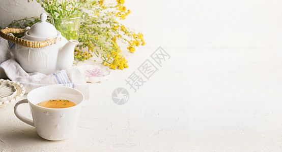 草药茶背景与杯黄茶,茶壶新鲜草药花白色桌子墙上机土豆茶野生药用植物为您的产品图片