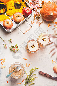 秋天的布局璃杯与苹果热苹果酒苹果覆盖葡萄酒与苹果片白色桌与向日葵,南瓜秋叶,顶部视图秋天的季节享受图片