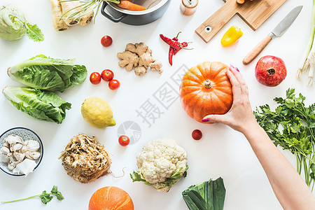 健康食品干净的季节饮食观念各种机蔬菜白色桌子背景与锅,切割板刀女手南瓜素食背景的风景图片