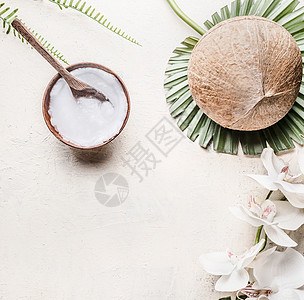 椰子油黄油木碗与勺子整个椰子热带树叶花,顶部的景观健康的植物脂肪来源素食化妆品图片