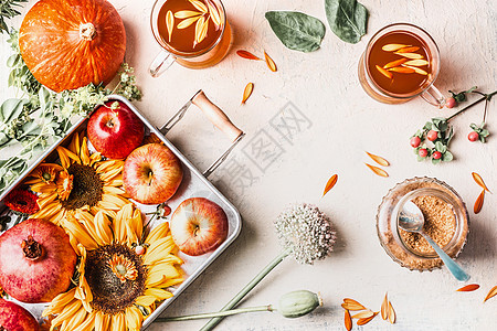 秋夏末与向日葵,南瓜,苹果,花草药茶白色桌上的杯子成的风景框架背景图片