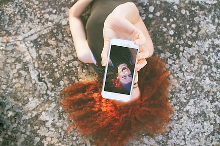 轻的美女用她的智能手机为社交媒体自拍图片