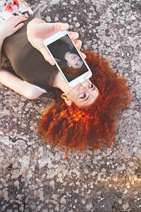 轻的美女用她的智能手机为社交媒体自拍图片