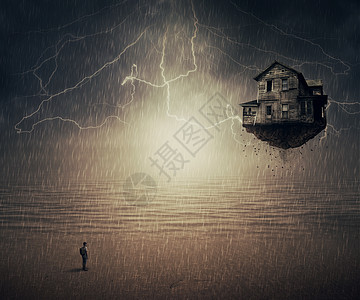 个人站雨中的超现实的后轮,个地上撕下的飞屋前,靠近海洋六感图片