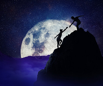 帮助朋友攀登山岩悬崖的人风险情况下的队合作信任满月的夜晚背景图片