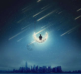 超现实的背景,个男孩坐新月上,个秋千,个繁星的夜晚,个大城市上空背景图片