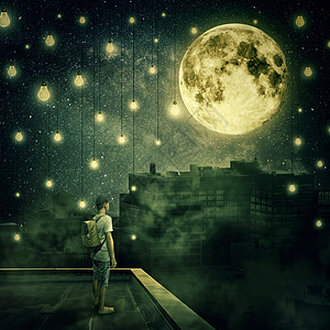 小男孩呆屋顶上看着满月神秘的夜晚,悬浮的灯泡像星星样笼罩着雾城图片