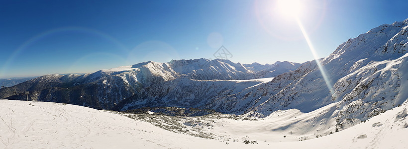 阳光明媚的冬日全景雪山的顶部图片