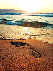 人类海滩上的足迹,金色的沙子,海上日出的前图片