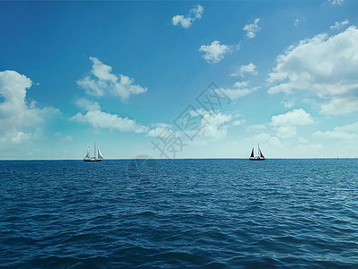 阳光明媚的日子里,两艘船漂浮海洋上图片