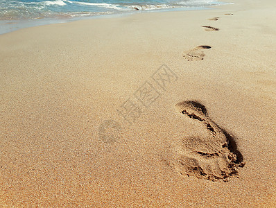 靠近水的海滩上沙滩上脚印的特写旅程图片