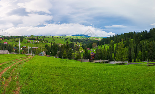 风景如画的春山景象与木制的劈轨围栏穿过片绿色郁郁葱葱的牧场,条乡村公路山谷上的老房子被松树林包围亚布隆尼亚,乌克兰图片