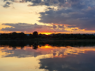 美丽的日落城市的地平线上,个寂静的夏季傍晚,平静的湖水上倒影图片