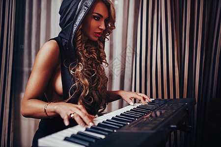 轻女子音乐家感时尚肖像夜间室内弹钢琴女音乐家肖像图片
