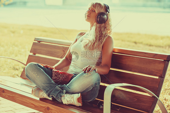 轻的少女风格的女人早上坐长凳上听音乐温暖的阳光少女风格的女人图片