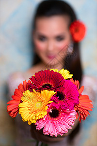 轻的亚洲女人着红花专注于花轻的亚洲女人图片