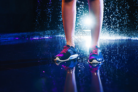 女人的腿运动运动鞋站水上工作室与雨滴内部腿与运动运动鞋图片