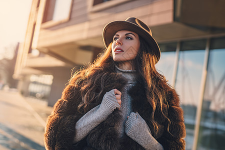 轻的女人穿着温暖的衣服帽子,秋天的日落肖像城市女人城市肖像图片