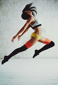 轻的苗条运动黑发女人跳墙上的背景轻的体育女子跳跃图片