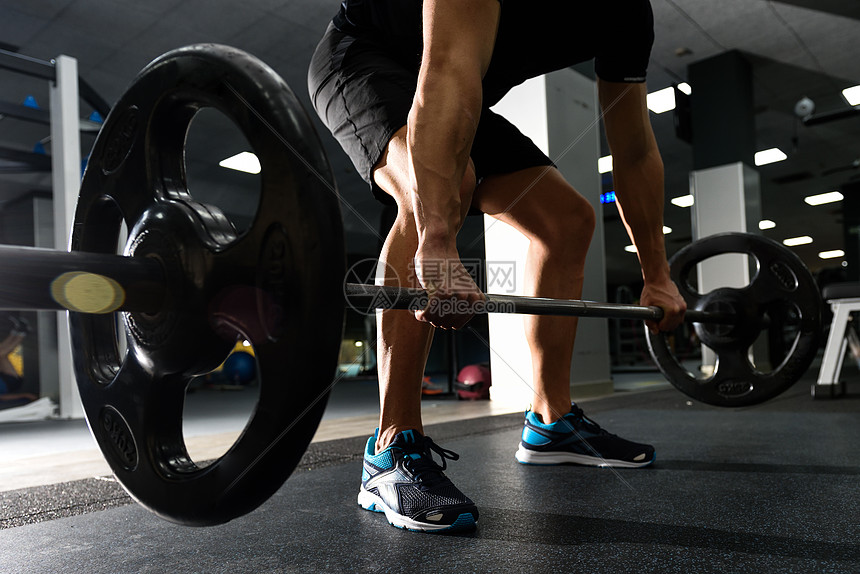 健身房用杠铃进行举重锻炼的特写穿着运动服的男人图片