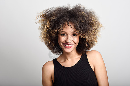 轻的黑人女人,留着AFRO的发型,微笑着穿着黑色连衣裙的女孩摄影棚拍摄图片