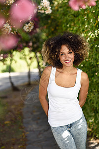 轻的黑人妇女,留着AFRO发型,城市公园微笑穿着白色T恤蓝色牛仔裤的混合女孩图片
