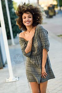 轻的混合女人,留着AFRO发型,城市背景下微笑穿休闲衣服的黑人女孩图片
