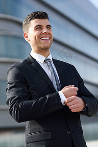 轻的商人现代办公楼附近穿着黑色西装领带蓝眼睛微笑的男人图片