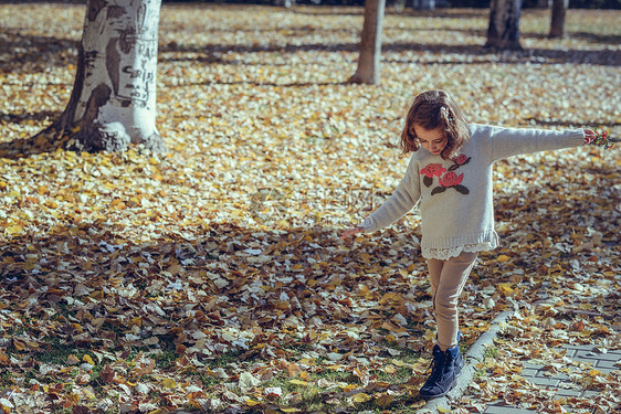 秋天,个小女孩城市公园里玩耍,穿着裤子运动衫,头发上戴着发夹图片