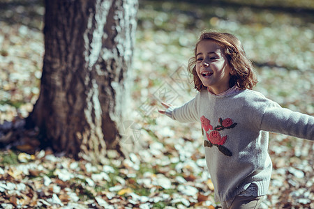 秋天,个小女孩城市公园里玩耍,穿着裤子运动衫,头发上戴着发夹图片