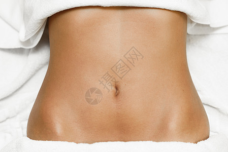棕色女腹部的顶部视图,躺水疗床上,用白色毛巾图片