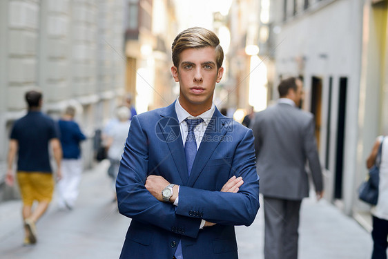 位吸引力的城市背景的轻商人的肖像,穿着蓝色西装,系着领带金发图片