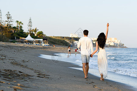 轻的幸福夫妇美丽的海滩上散步穿着休闲衣服的趣的男人女人后视镜图片