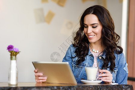 轻的女人坐室内喝咖啡,看着她的平板电脑20多岁的轻现代白种人女咖啡馆城市生活方式图片