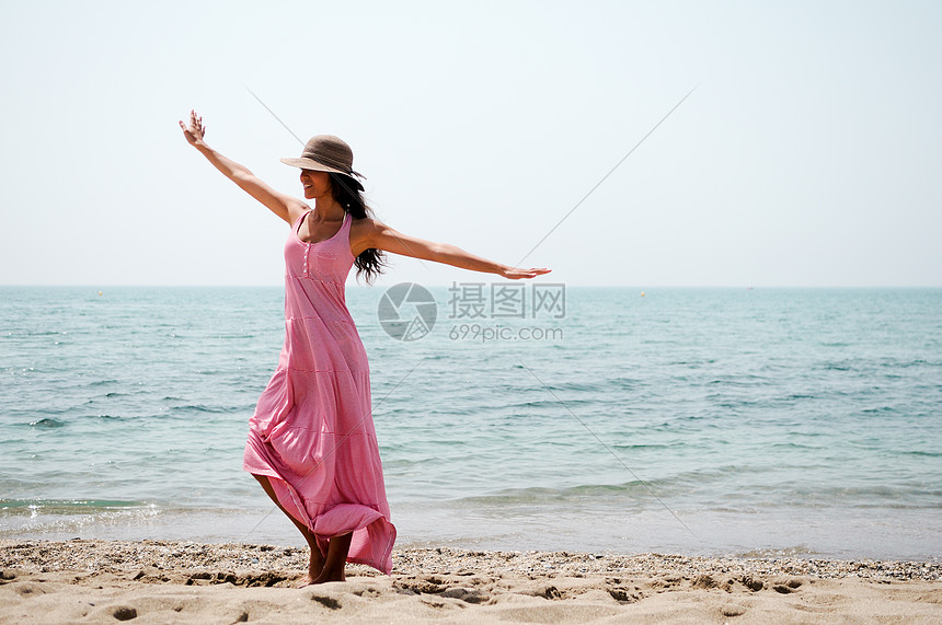 热带海滩上位穿着粉红色长裙的美女的肖像图片