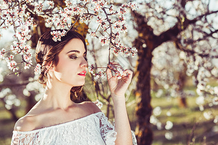 春天花圃里轻女子的肖像杏仁花开花了穿白色衣服的女孩像新娘图片