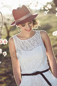 春天花圃里轻女子的肖像杏仁花开着白色的连衣裙帽子图片