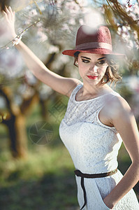 春天花圃里轻女子的肖像杏仁花开着白色的连衣裙帽子图片
