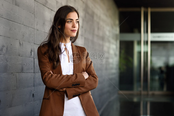 站办公楼外的轻女商人穿正式衣服的漂亮女人穿着棕色夹克裤子的轻女孩图片