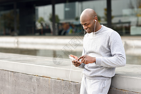 吸引力的黑人城市背景下用耳机听音乐男户外运动服图片