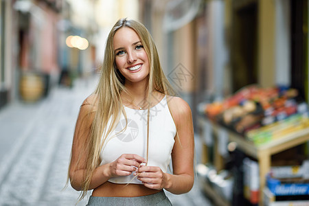 城市背景中微笑的轻女人金发女孩穿着漂亮的头发休闲服街上直发型图片