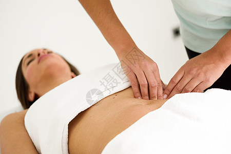 双手按摩女腹部治疗师腹部施加压力水疗沙龙接受按摩的女人图片