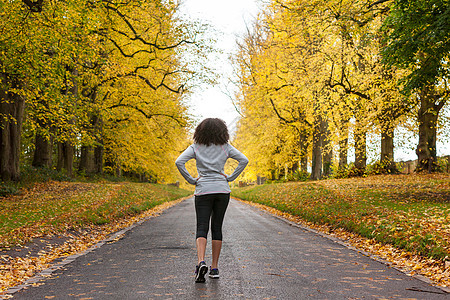 美丽的混合种族非裔美国轻女子少女准备健身跑步慢跑秋天的道路上倒下的树图片