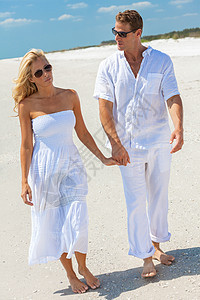 悲伤体贴的男人女人浪漫的夫妇穿着白色的衣服太阳镜,手牵着手走个荒凉的热带海滩上,蓝天清澈,关系问题的图片
