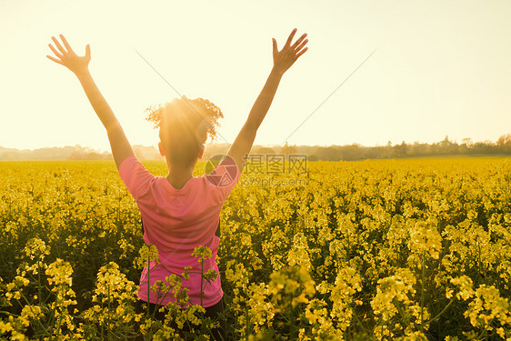 混合种族非裔美国女孩,女青,女运动员,跑步少,金色的日落日出的手臂,黄花的田野庆祝图片