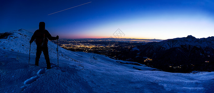 徒步旅行者看着冬天的山脉景观,而国际站国际站则夜空中留下了他的足迹意大利北部,欧洲图片
