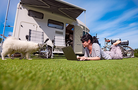 草地上的女人带着只狗看着笔记本电脑房车度假家庭度假旅行,度假旅行汽车VR图片