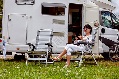 女人看着野营附近的平板电脑房车度假家庭度假旅行,度假旅行汽车房车无线连接信息通信技术图片
