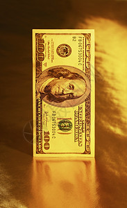 百美元额站黄金背景的反射上稳定的货币图片