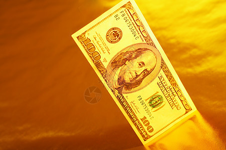 百美元额站黄金背景的反射上货币想象图片